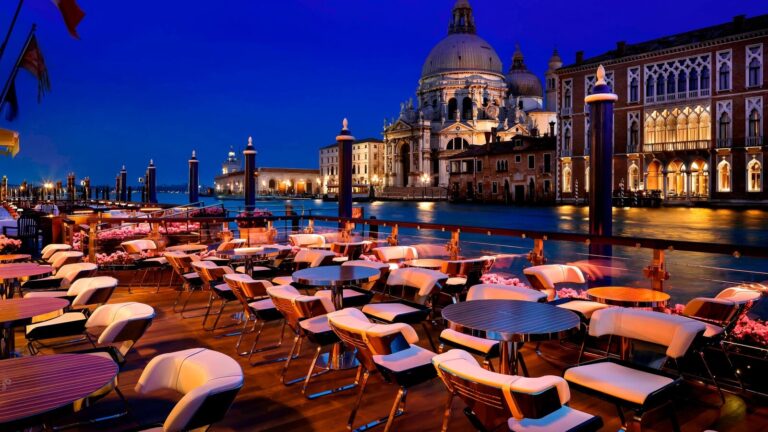 The canal-side terrace laid for dinner at night, candlelit above the water, The Gritti Palace