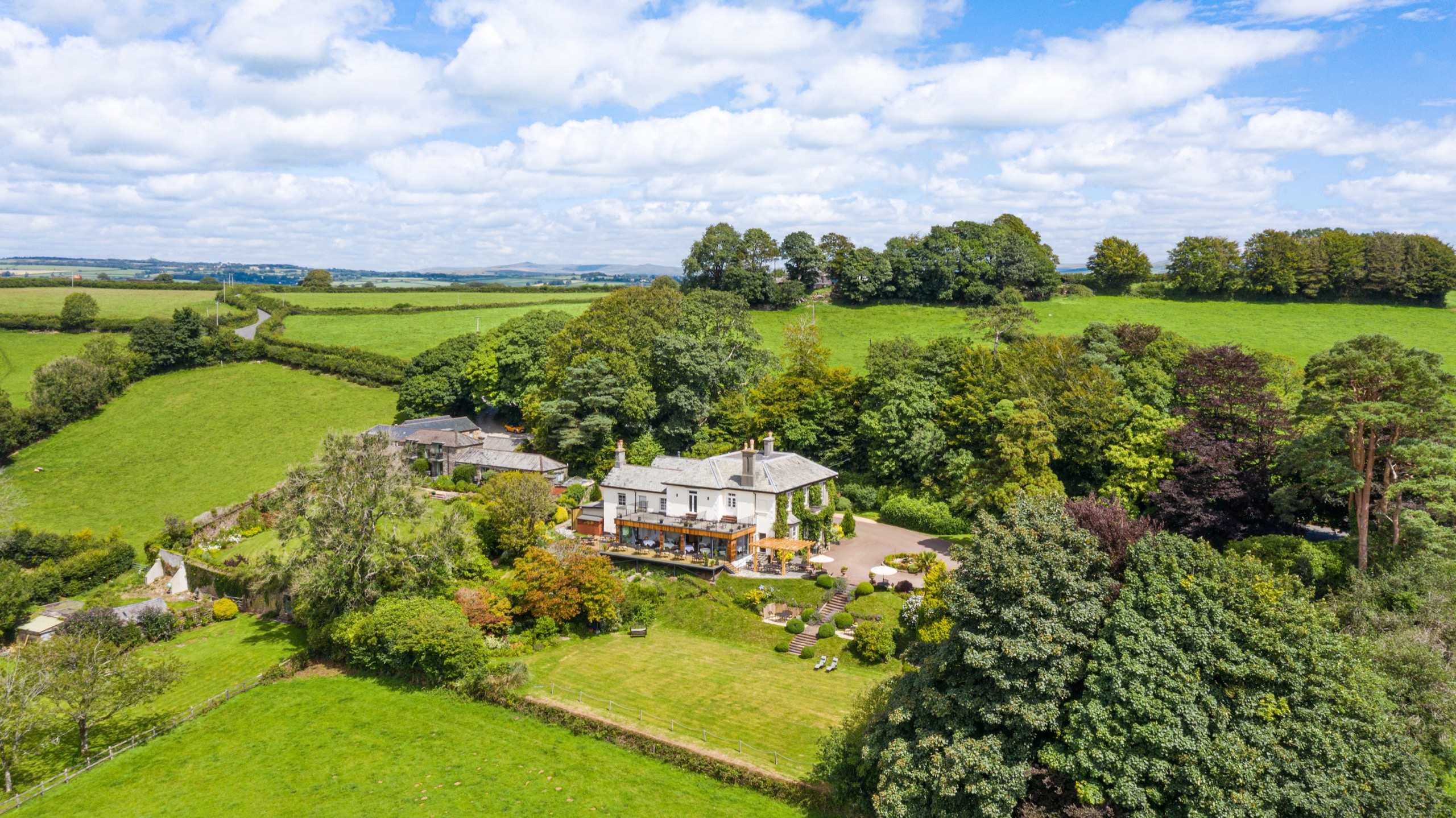 The hotel and its five acres of gardens seen from the air, surrounded by fields on the Devon side of the Tamar Valley, The Horn Of Plenty