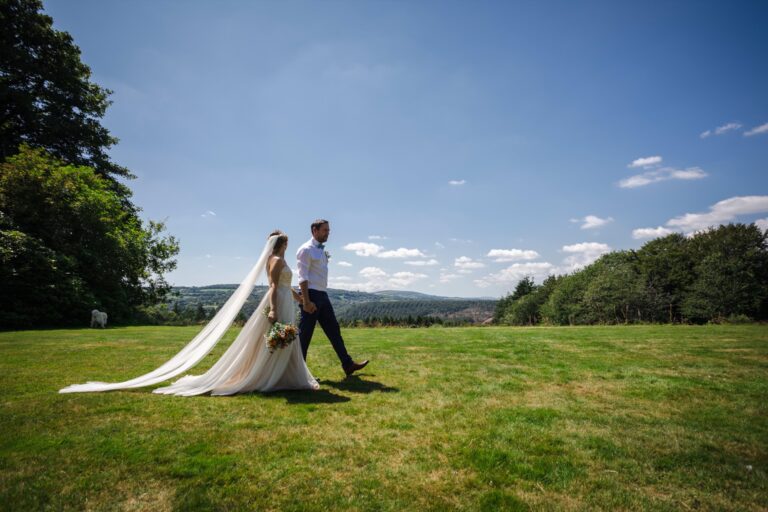 A couple walking across the top lawn on a clear summer day, with the far side of the valley behind, The Horn Of Plenty
