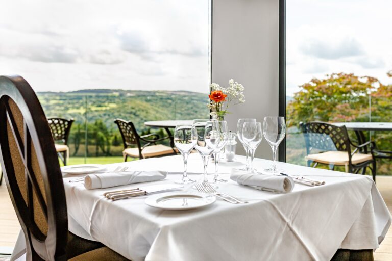 A laid restaurant table by the full-height windows, looking straight out over the valley, The Horn Of Plenty