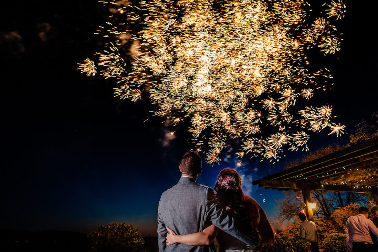 A couple watching fireworks over the garden from the terrace at night, The Horn Of Plenty