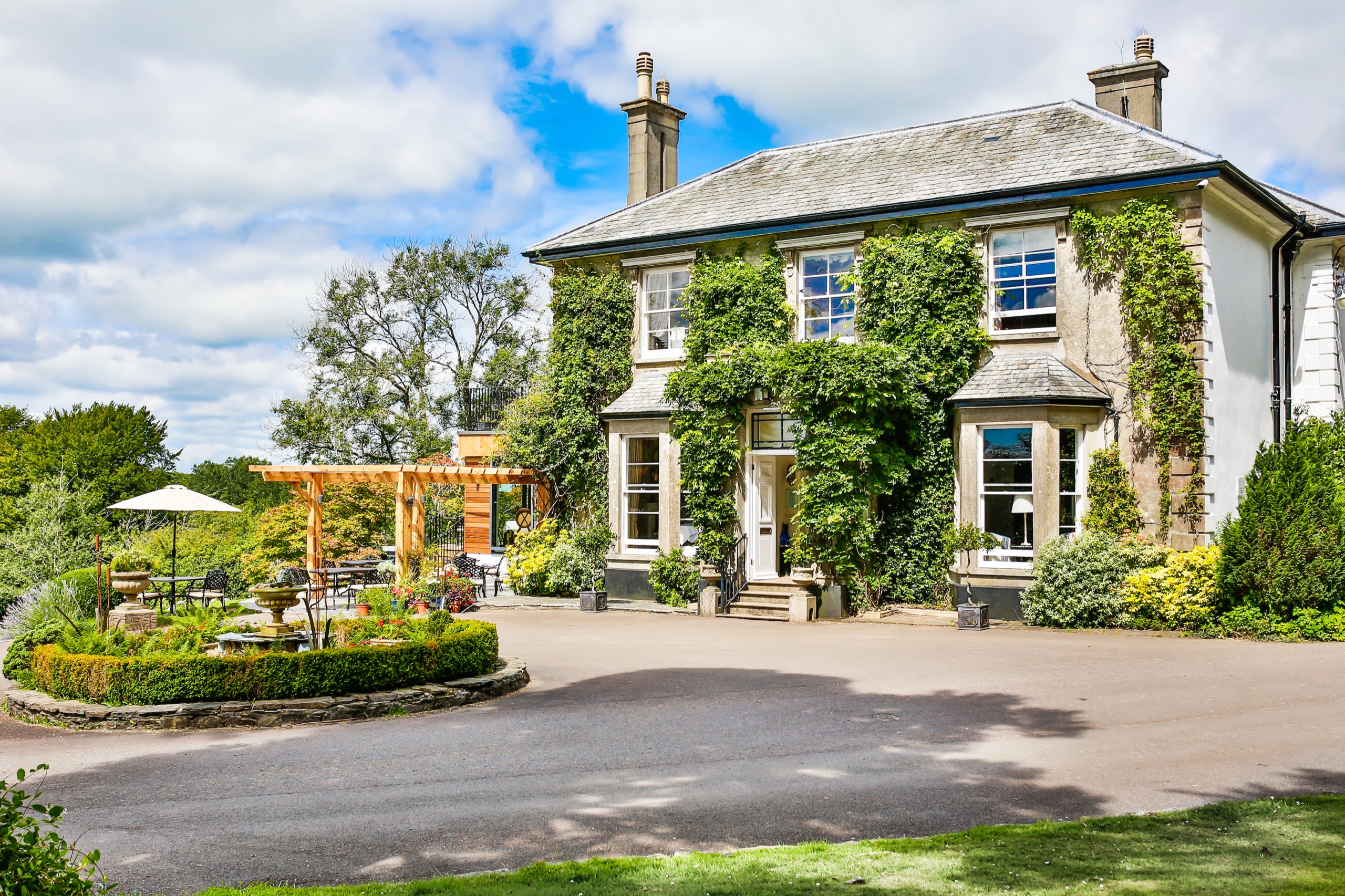 The ivy-covered Main House, built in 1866, with the turning circle and the restaurant pergola to one side, The Horn Of Plenty