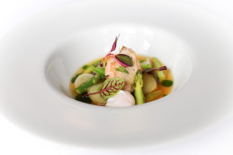 A clear consomme with quail, asparagus and spring vegetables, plated in the restaurant, The Horn Of Plenty