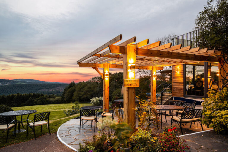 The oak pergola and stone terrace at sunset, with the valley falling away behind, The Horn Of Plenty
