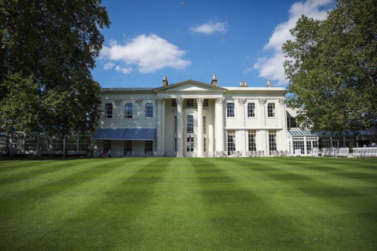The white clubhouse and its portico seen across the striped front lawn, The Hurlingham Club