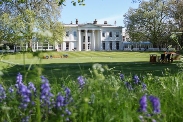 The clubhouse beyond the croquet lawn, with spring bluebells in the foreground, The Hurlingham Club