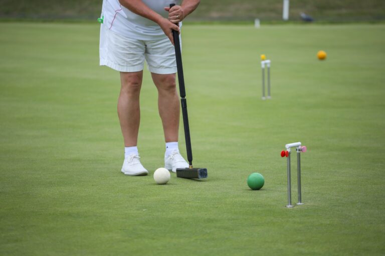 A croquet player lining up a shot through the hoop on the championship lawn, The Hurlingham Club