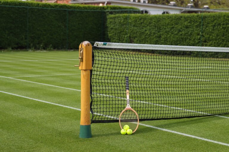 A grass tennis court with a classic wooden racquet resting against the net, The Hurlingham Club