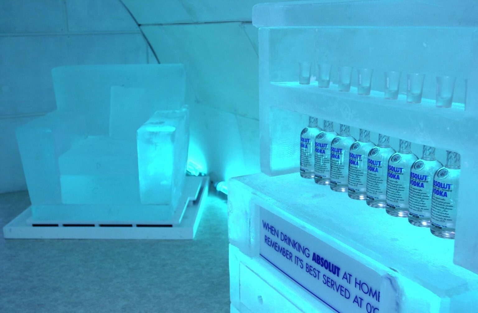 An ice bar room lit in blue, with bottles set into the ice shelving