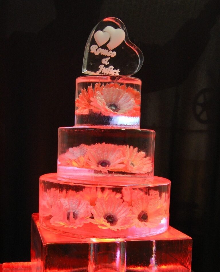 A three tier ice wedding cake sculpture with gerberas frozen inside, lit from below, The Ice Box