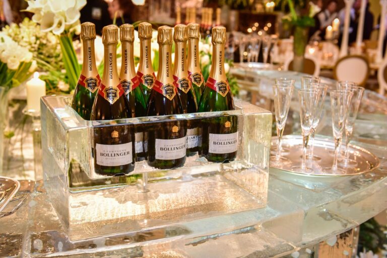 A block of ice holding chilled champagne bottles on a styled table, The Ice Box