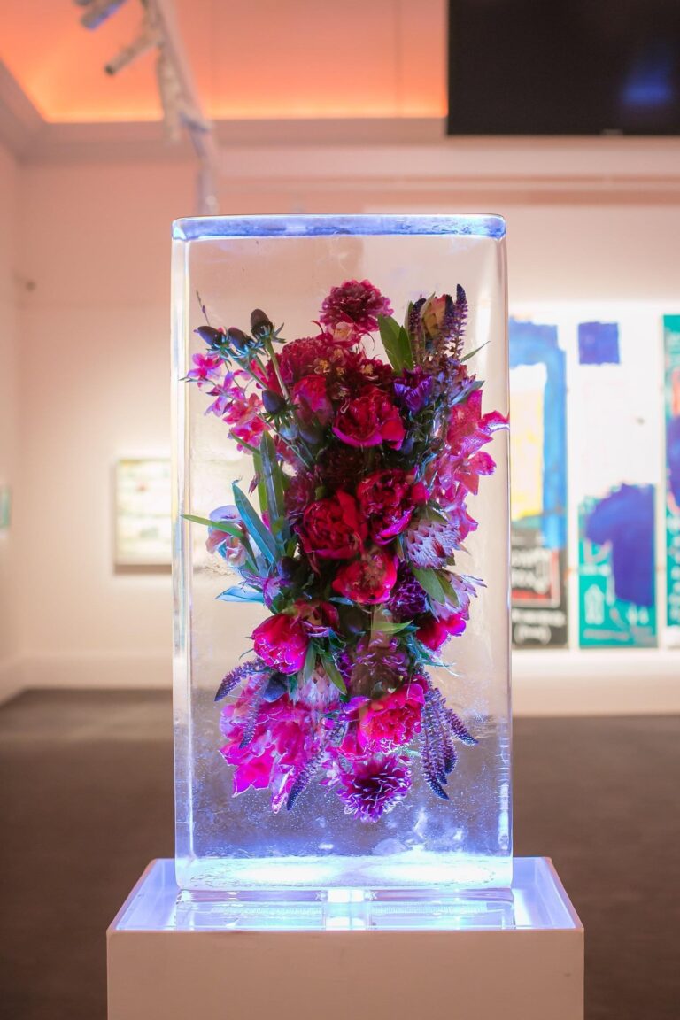 A 1m block of ice with pink and red flowers frozen inside, lit from below, The Ice Box