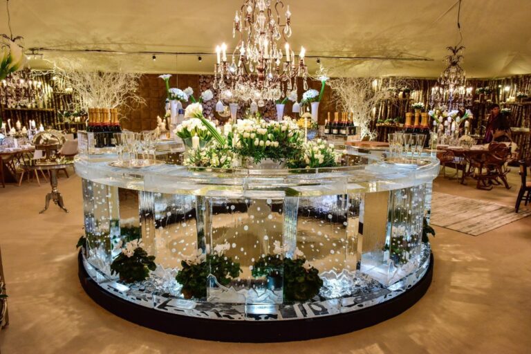 A 4m circular ice bar dressed with flowers and greenery under a chandelier, for a private wedding, The Ice Box