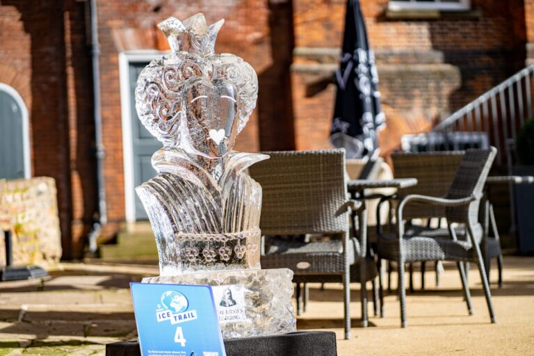 A carved ice queen of hearts on a plinth in a courtyard, The Ice Box