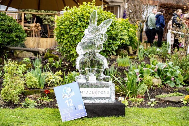 A carved ice white rabbit among garden planting, The Ice Box