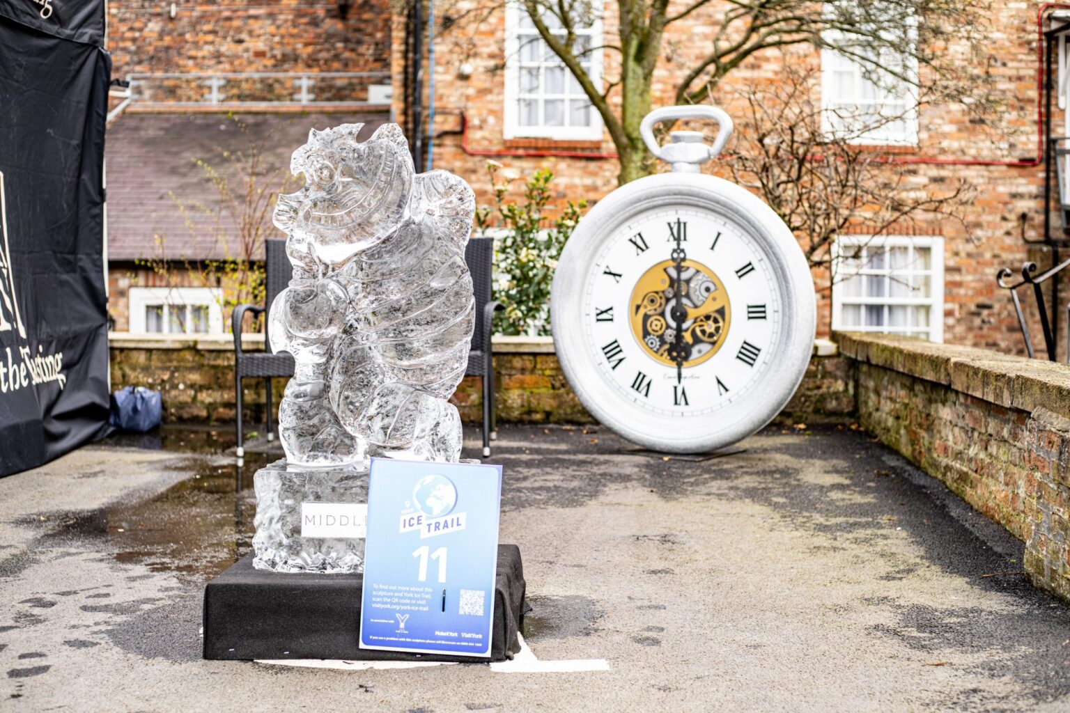 A carved ice Cheshire Cat beside a giant pocket watch
