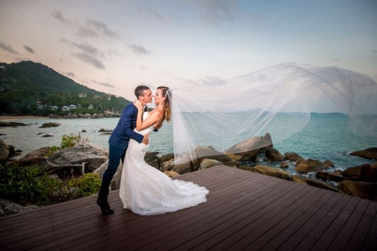 A couple on the wooden deck with the coast behind them, The Kala Samui