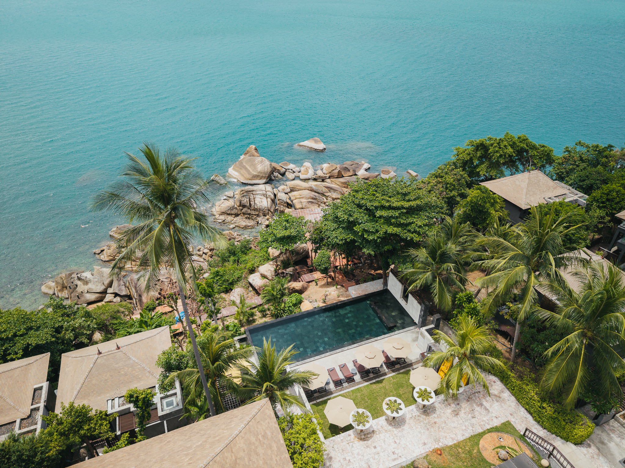 Aerial view of the pool and granite rocks along the cliffside coastline, The Kala Samui