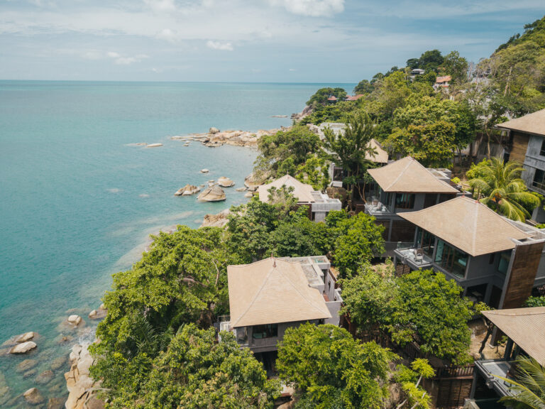 Aerial view of villa roofs stepping down the hillside to the Gulf of Thailand, The Kala Samui