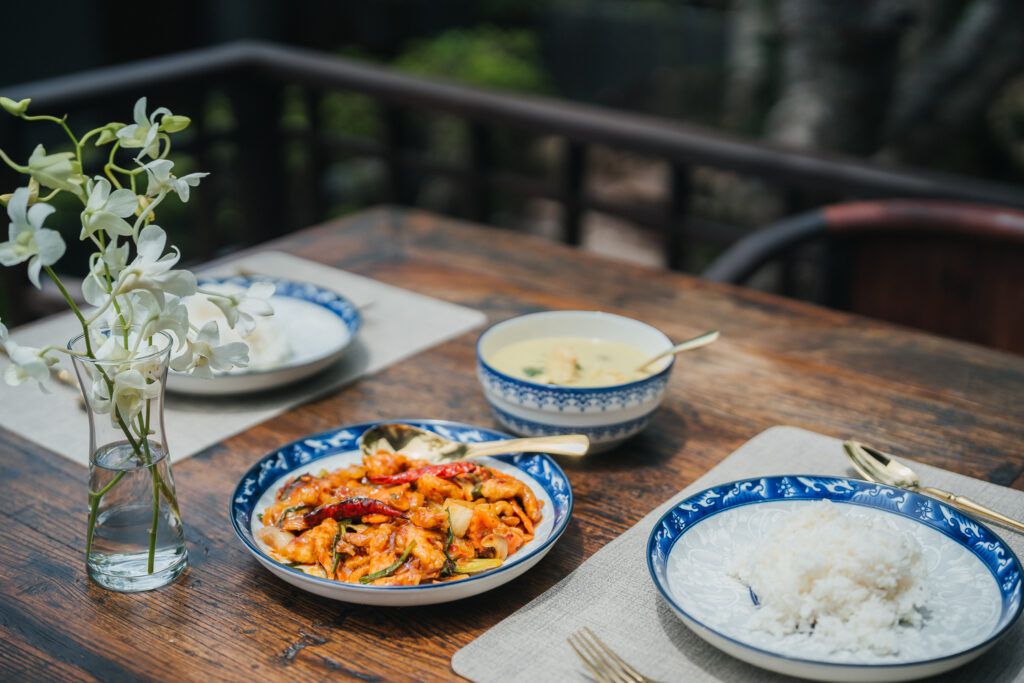 Thai dishes and rice served at a wooden table, The Kala Samui