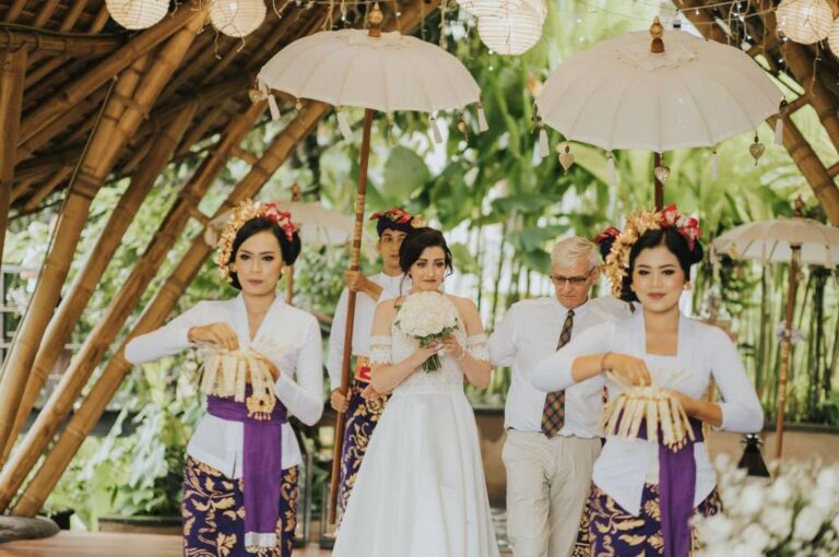 A bride walking in with Balinese attendants under white parasols, The Kayon Jungle Resort