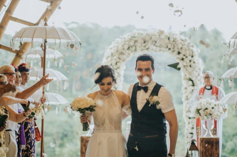 A couple after their ceremony beneath a flower arch, The Kayon Jungle Resort