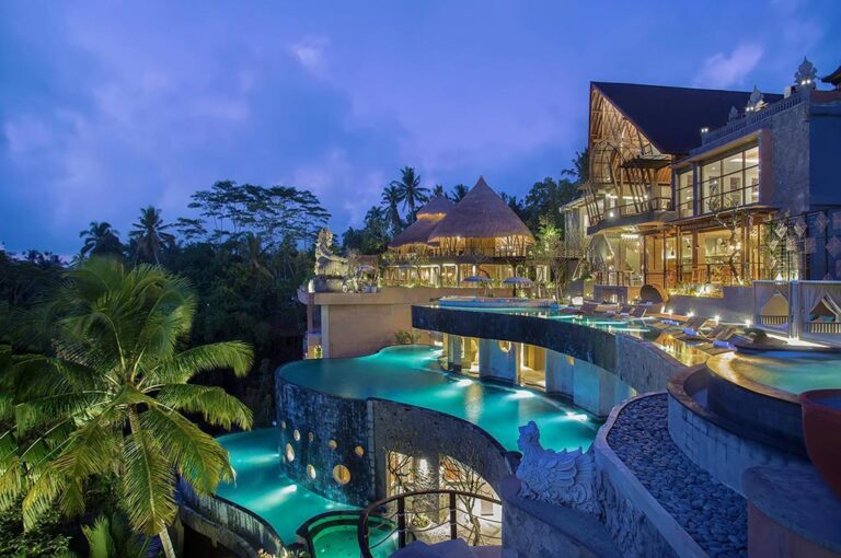 The resort buildings and pools lit at night, The Kayon Jungle Resort