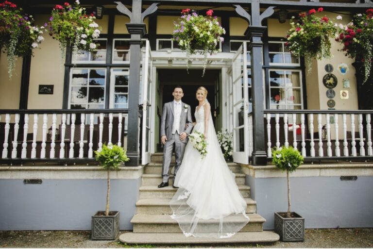 Newlyweds on the white balustraded veranda steps, The Lake Country House Hotel & Spa