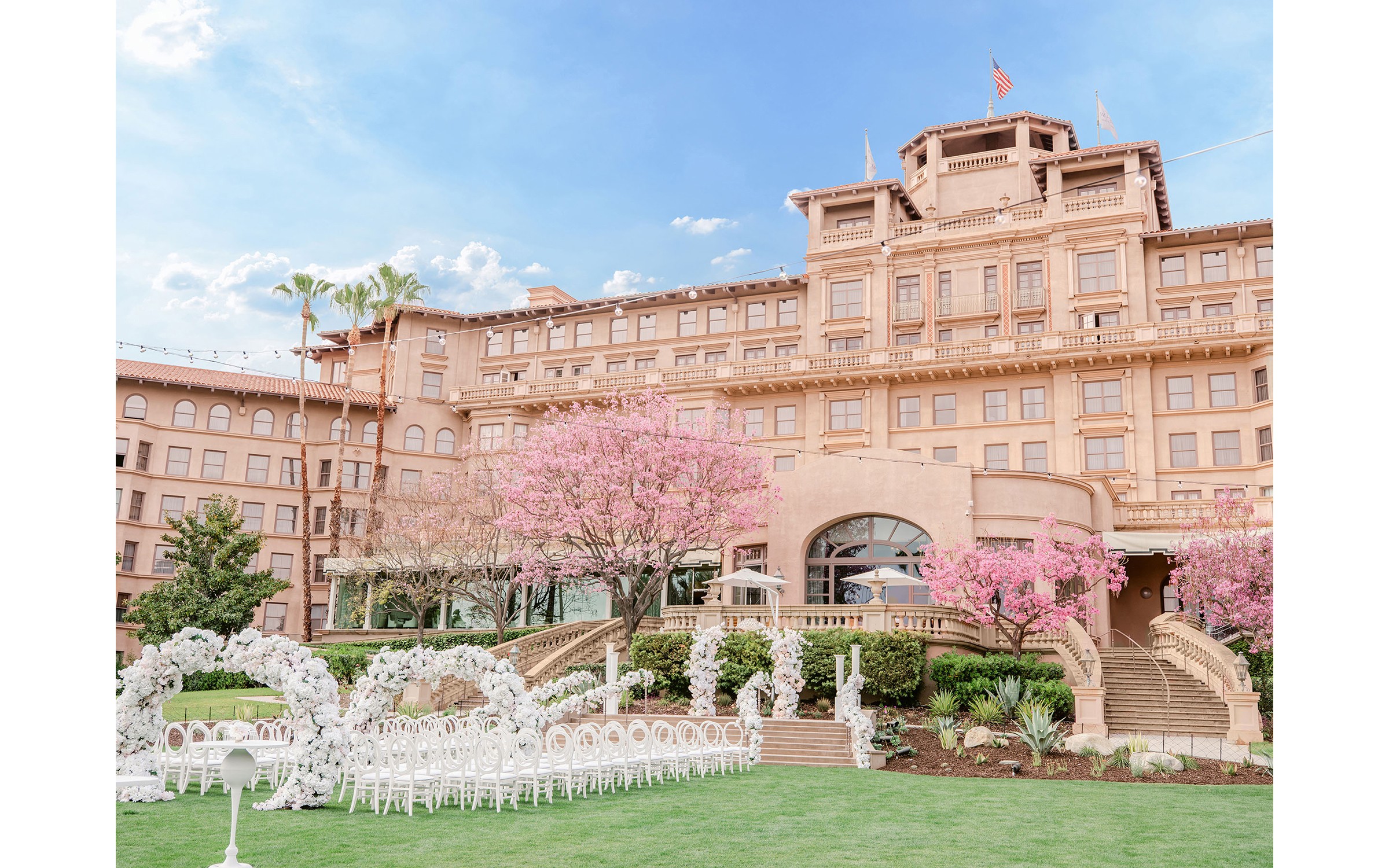 Ceremony chairs and floral arches set on the lawn below the hotel, The Langham Huntington Pasadena