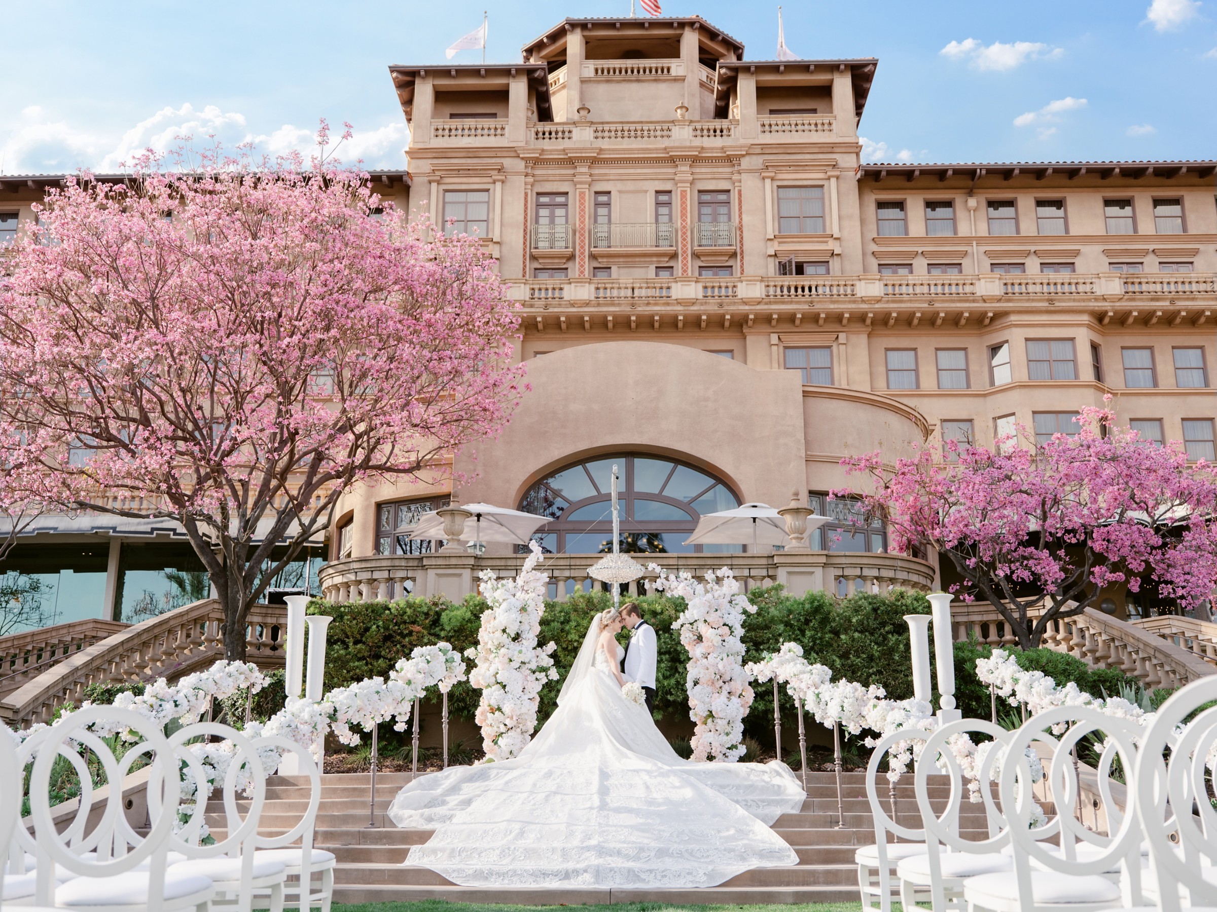 A ceremony aisle with white chairs and floral arch in the Horseshoe Garden, The Langham Huntington Pasadena