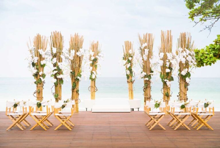 Ceremony set-up with tall flower stands on a deck facing the beach, The Library