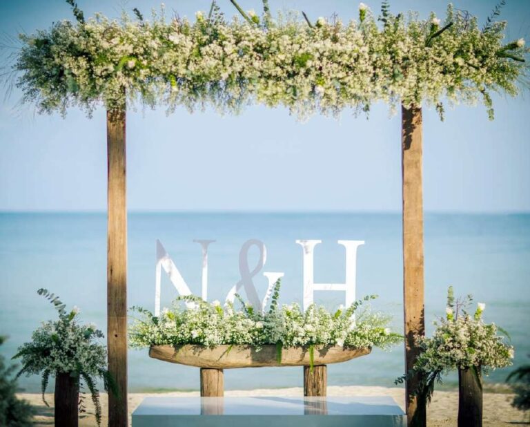 Flower-topped wooden arch with an initials sign at the water's edge, The Library