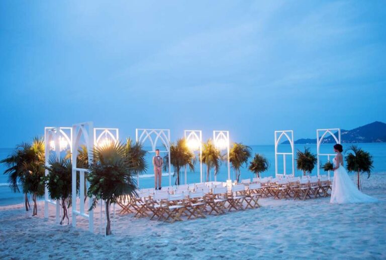 Beach ceremony set-up at dusk with arched frames and chairs, The Library