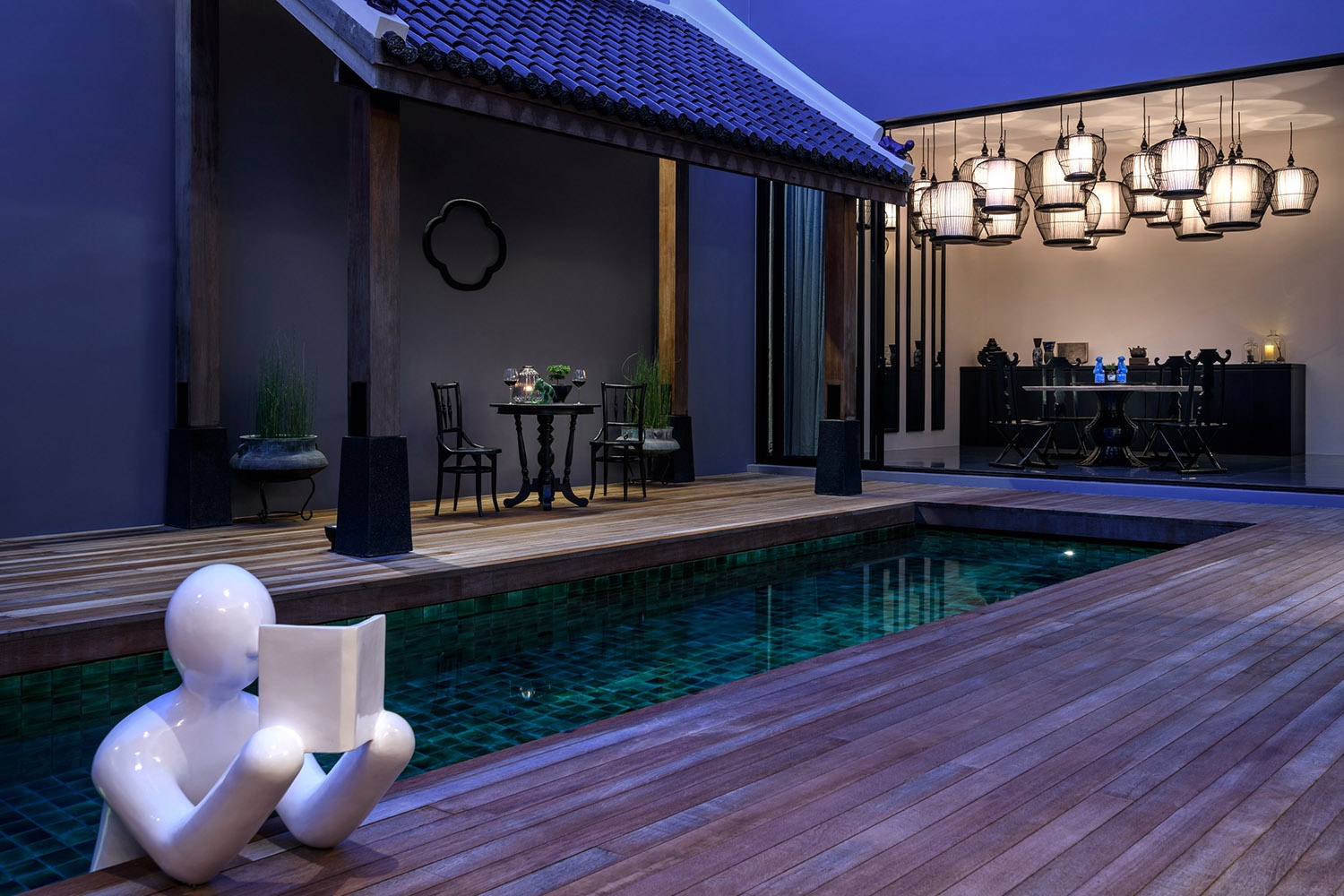 Private pool, deck and lantern-lit dining pavilion at The Editor villa at dusk, The Library
