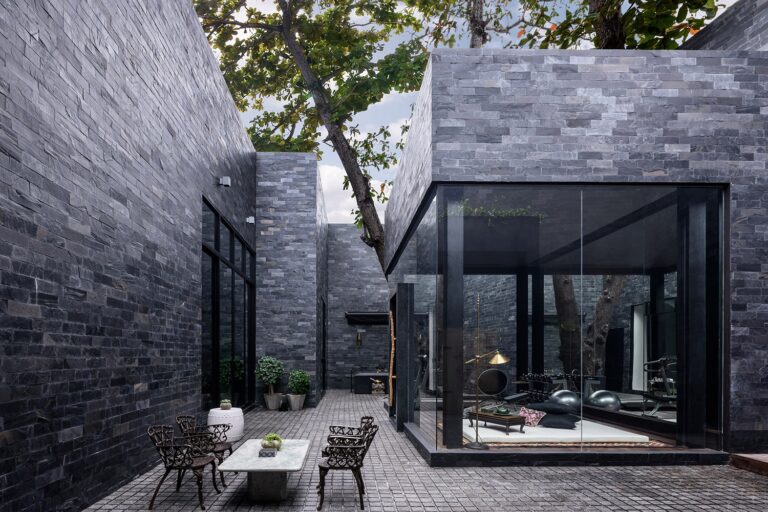 Slate-walled courtyard and glass-fronted gym pavilion at The Writer villa, The Library