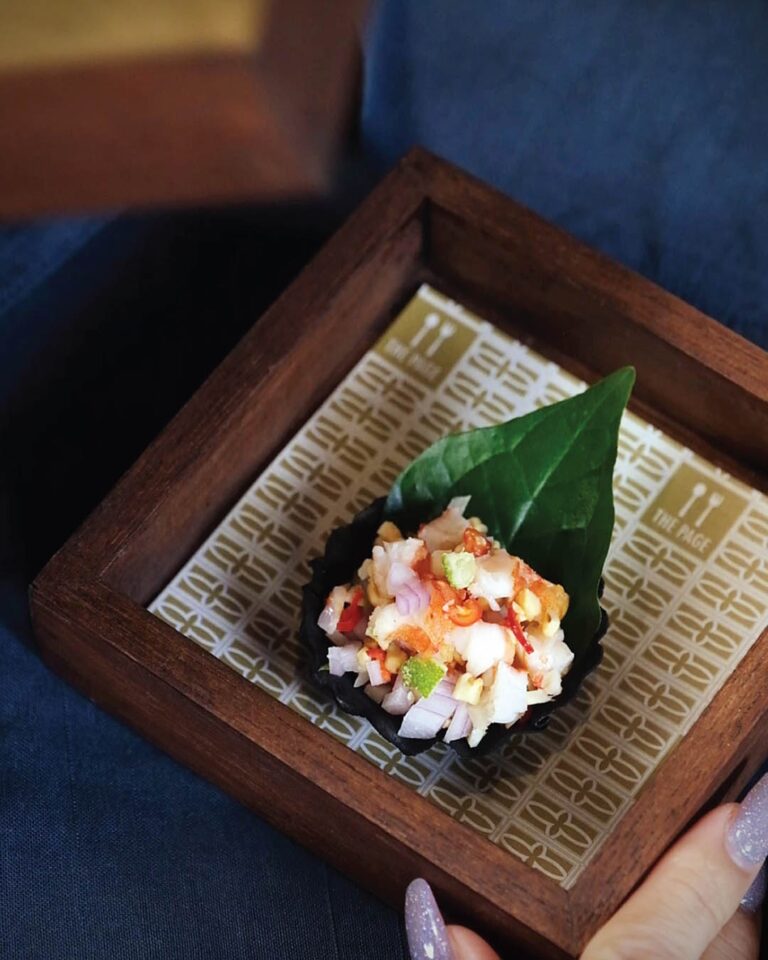 A plated dish served in a wooden tray with a leaf garnish, The Library