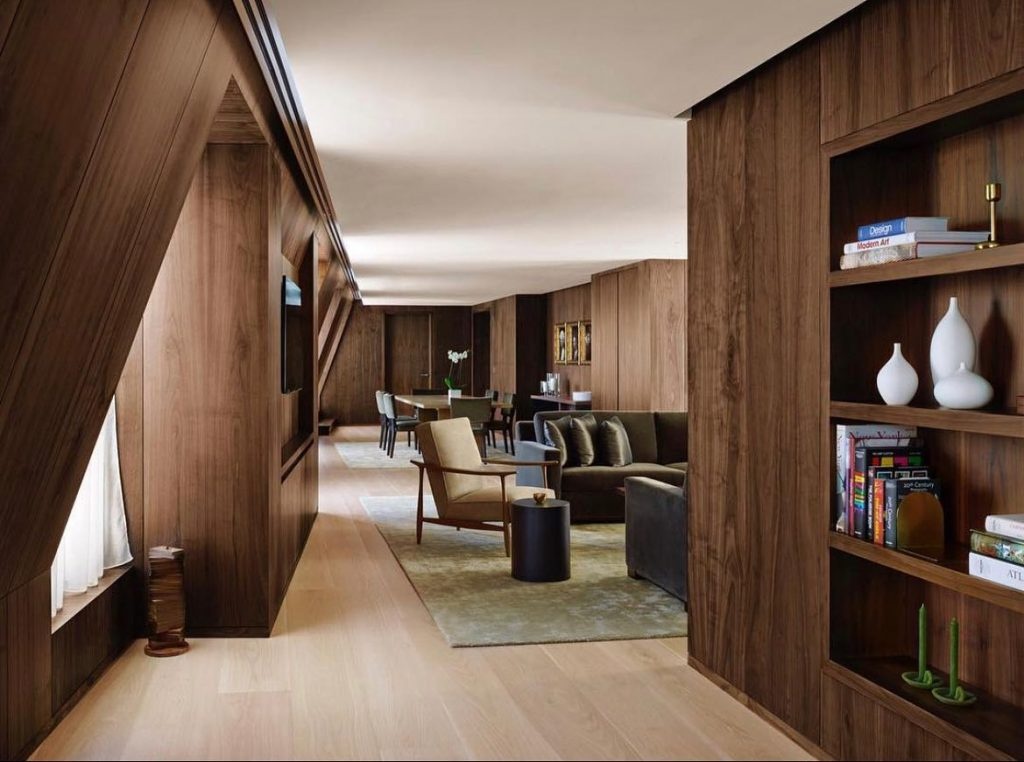 A walnut-panelled suite lounge with bookshelves and soft seating, The London EDITION