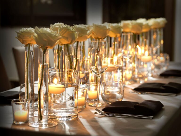 Candles and single white roses in glass vases along a wedding table, The Londoner
