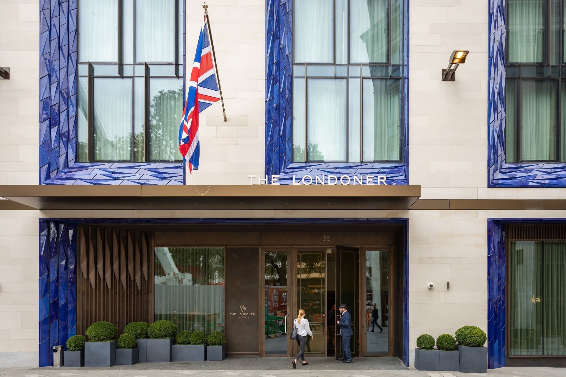 The main hotel entrance at 38 Leicester Square, with clipped box planters beneath the name canopy, The Londoner