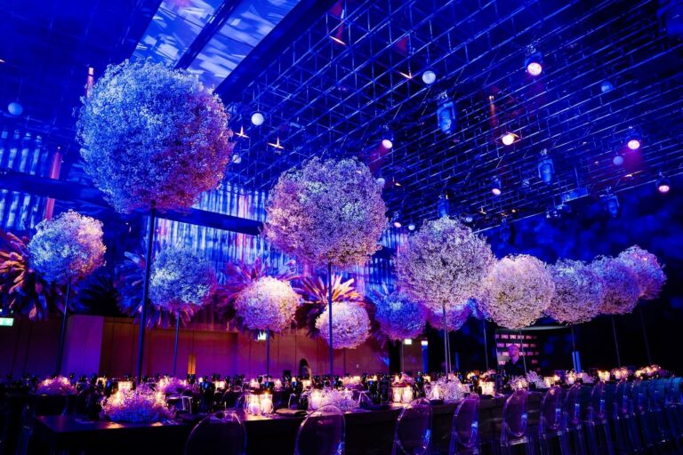 Tall globes of white hydrangea above a long table in the Ballroom, lit in blue and violet, The Londoner
