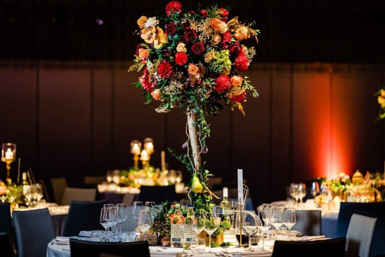 A tall centrepiece of red and orange flowers over round tables in the Ballroom, The Londoner