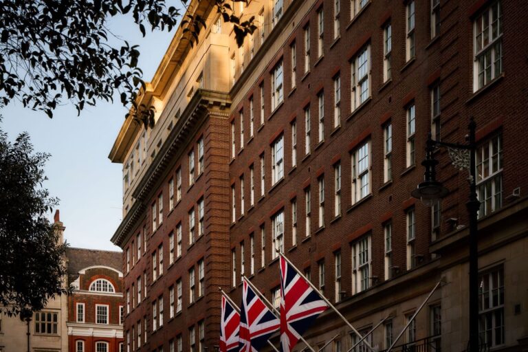 Looking up at the 1920s brick and stone facade with Union flags over the street, The May Fair