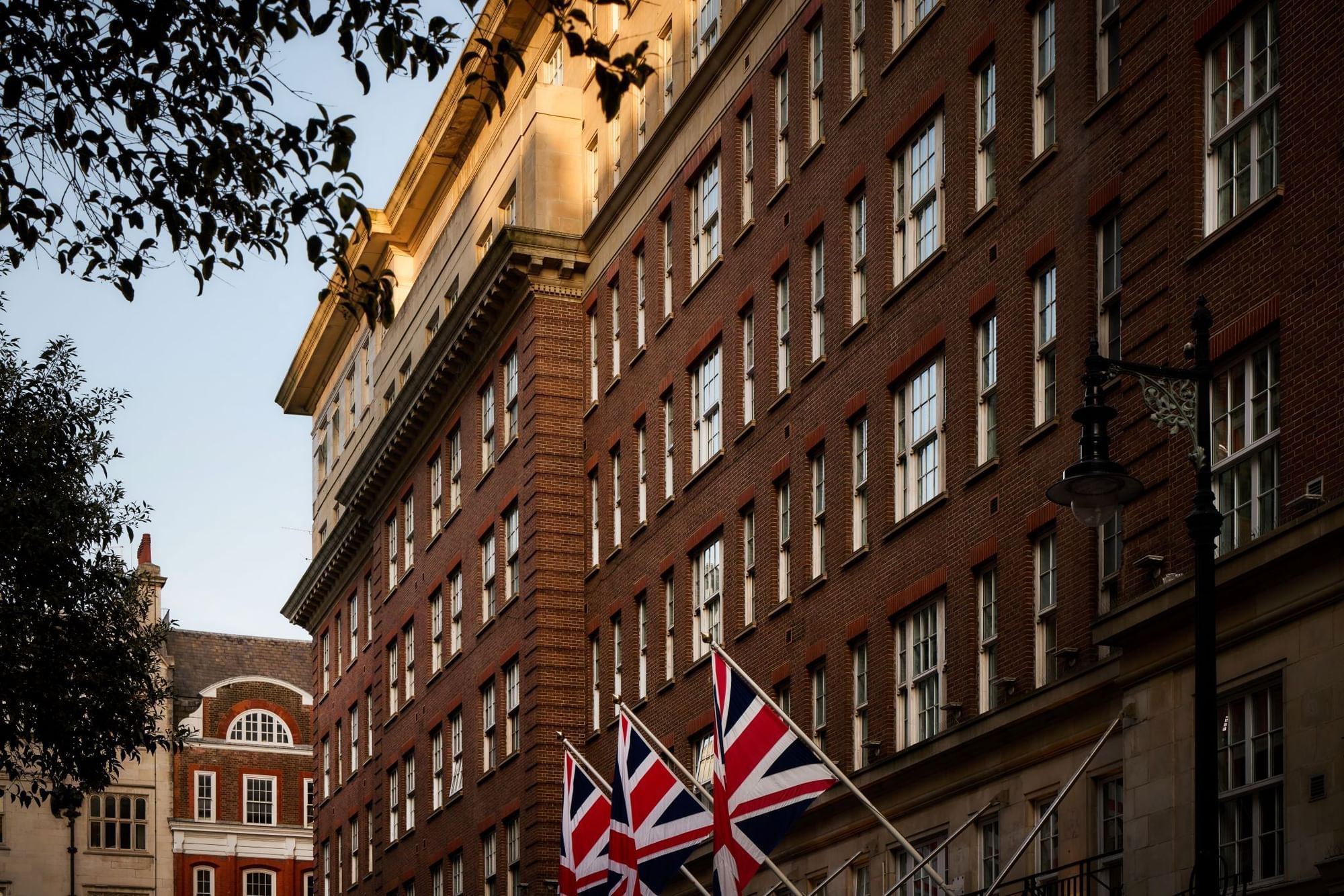 Looking up at the 1920s brick and stone facade with Union flags over the street, The May Fair