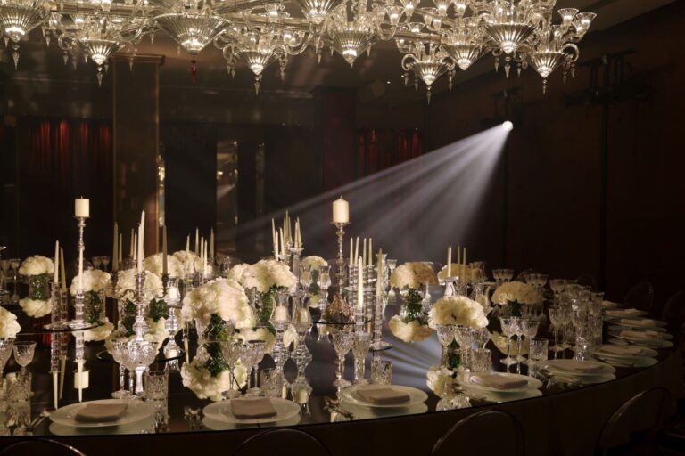 A mirrored table of white flowers and silver candlesticks under the glass chandelier in the Crystal Ballroom, The May Fair