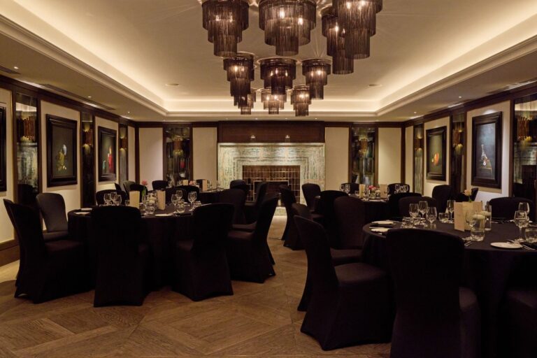 The Private Dining Room with round tables, walnut floor and its dark panelled walls, The May Fair