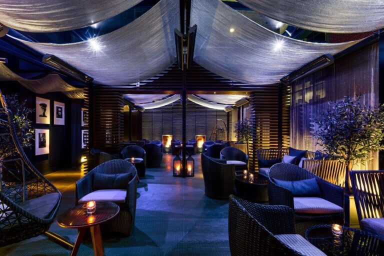 The May Fair Terrace in the evening, lit in blue with lanterns on the low tables, The May Fair