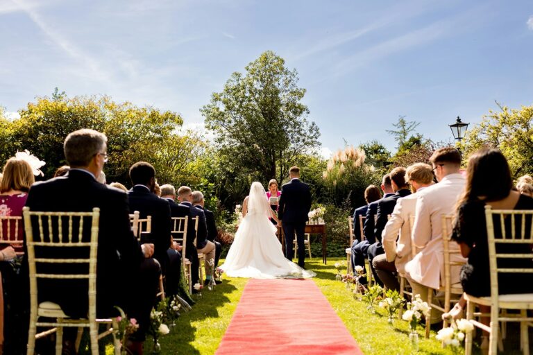 An outdoor ceremony in the garden, guests seated either side of the aisle, The Montagu Arms Hotel