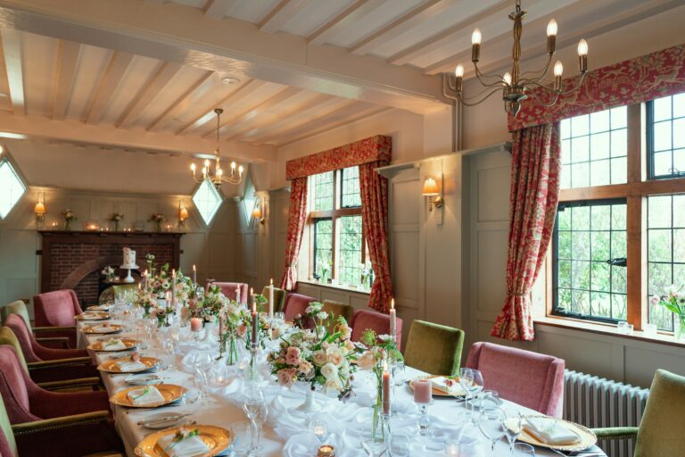 The wedding breakfast under the beamed ceiling, velvet chairs and full glassware, The Montagu Arms Hotel
