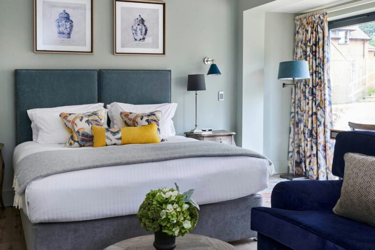 A bright Courtyard bedroom with a teal upholstered headboard, The Montagu Arms Hotel