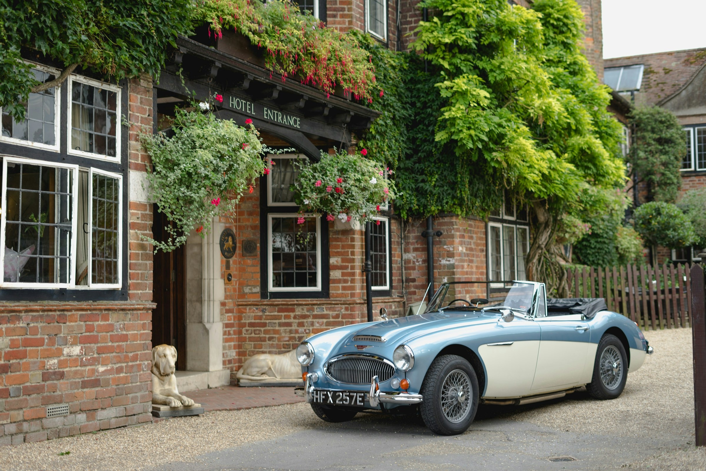 The hotel entrance, ivy and fuchsia over red brick, a classic Austin-Healey on the gravel, The Montagu Arms Hotel
